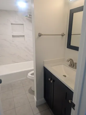 a bathroom with a granite countertop sink a toilet and bathtub