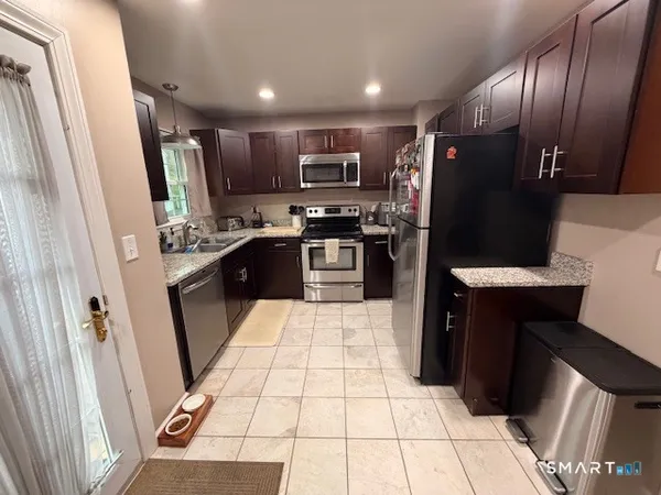 a kitchen with stainless steel appliances kitchen island granite countertop a refrigerator and a sink