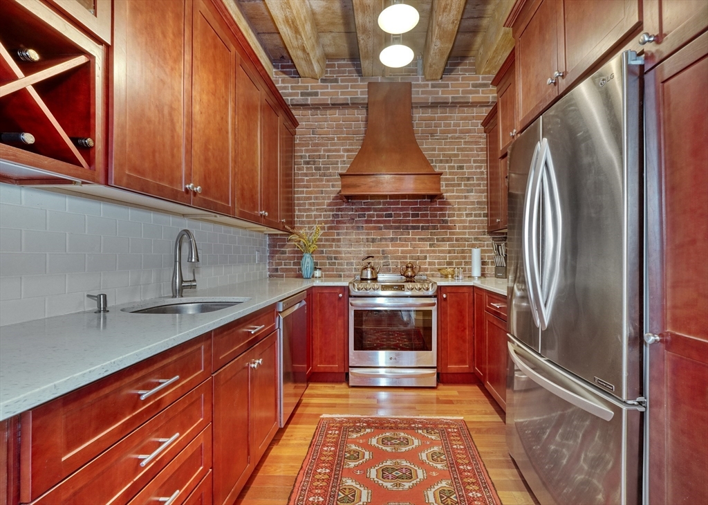 28-32 Atlantic Avenue, Unit 424 Boston, MA 02110 - Photo 10 of 38 a kitchen with stainless steel appliances granite countertop a sink and wooden cabinets