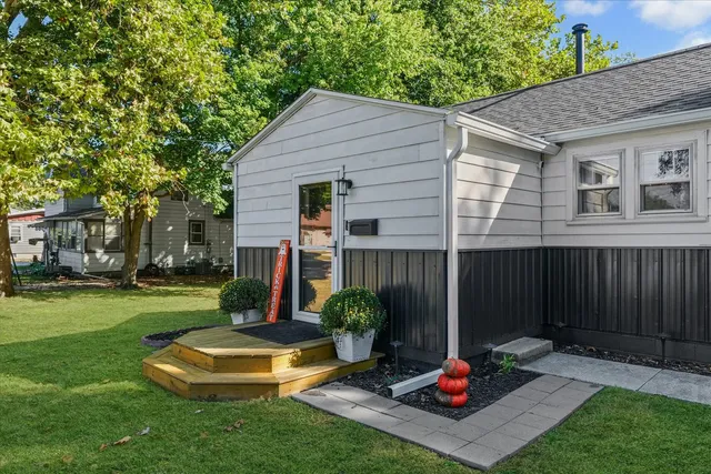 a view of a backyard with table and chairs potted plants and large tree