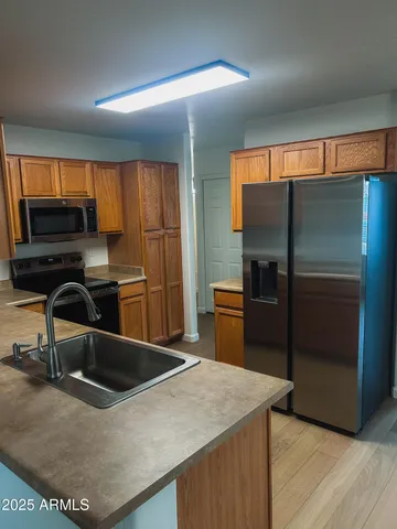 a kitchen with stainless steel appliances kitchen island granite countertop a refrigerator and a sink