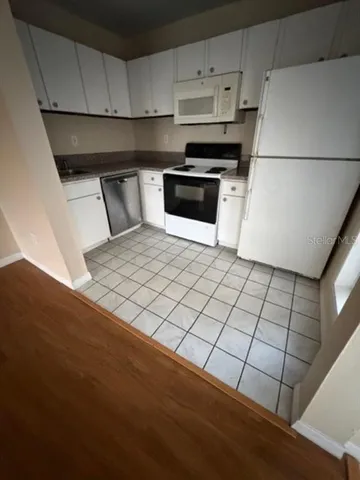 a kitchen with a sink a stove top oven and white cabinets