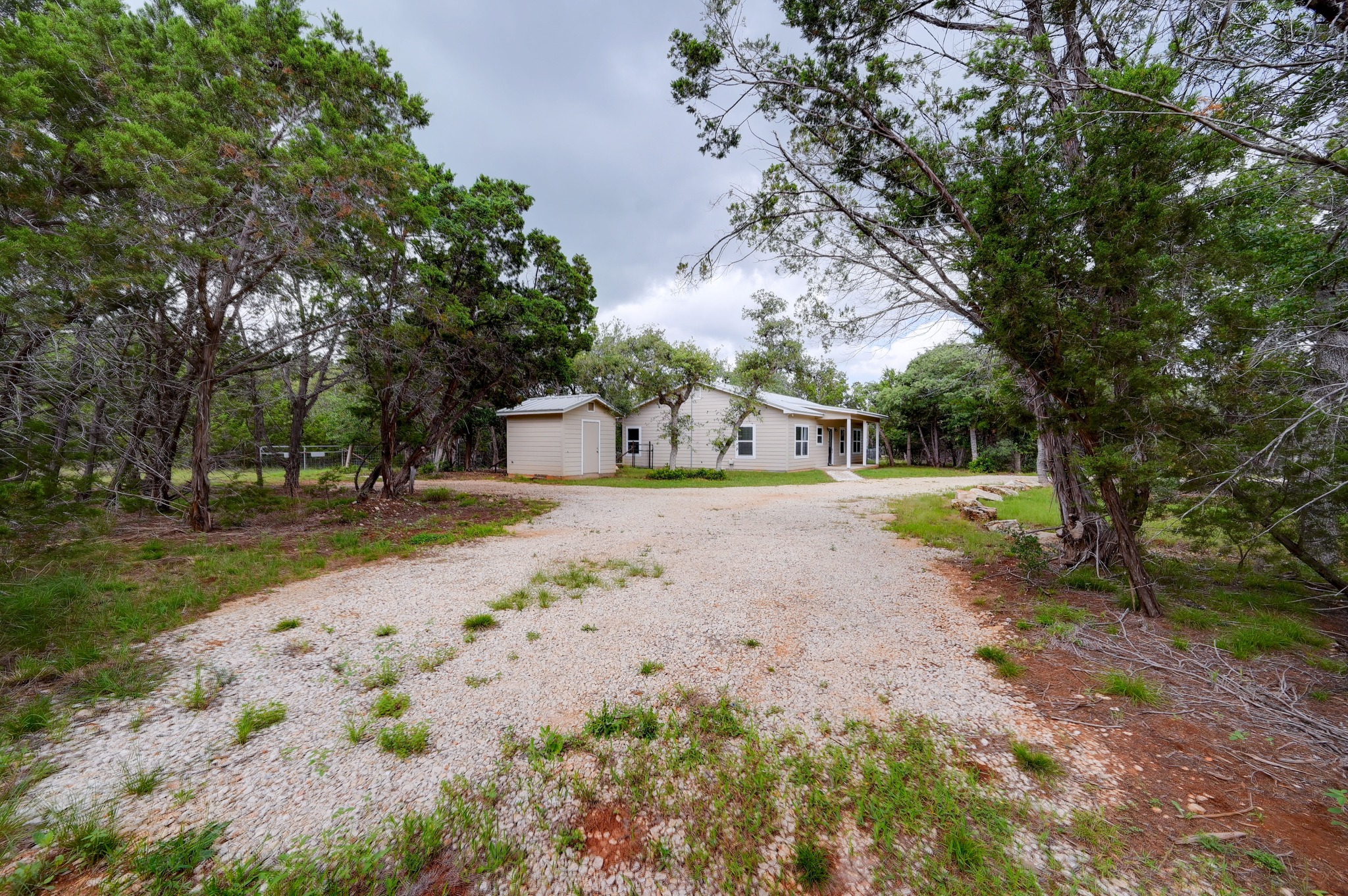 231 North Rainbow Ranch Road Wimberley, TX 78676 - Photo 29 of 40 A private gravel driveway leads to a secluded home nestled amongst natural landscaping and mature trees.