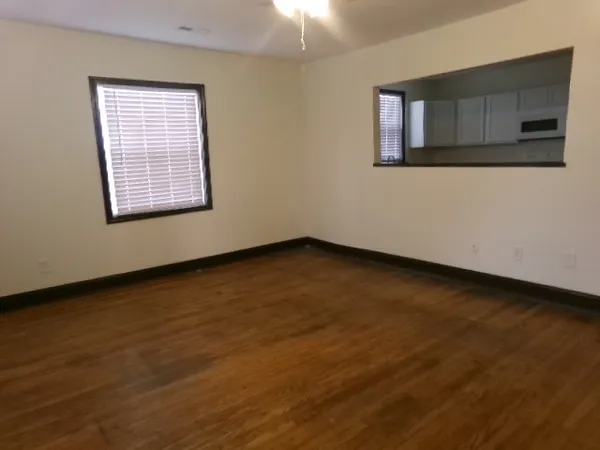 a view of an empty room with wooden floor and a window