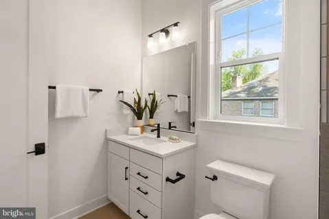 a bathroom with a sink vanity granite toilet and a mirror