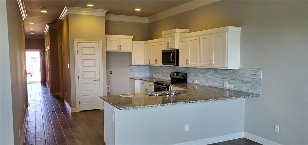 100 Bailey Kay Court, Unit B Jarrell, TX 76537 - Photo 3 of 14 Kitchen featuring dark stone countertops, decorative backsplash, white cabinets, a peninsula, and ornamental molding