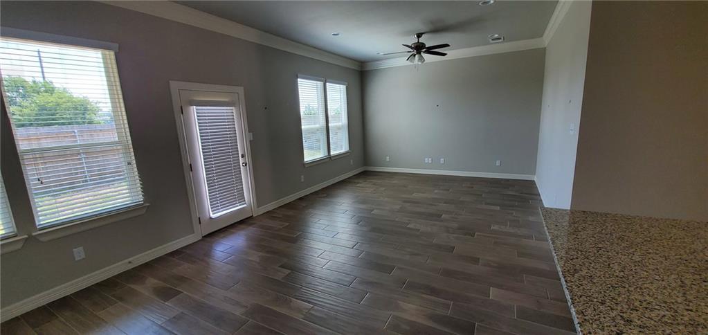 100 Bailey Kay Court, Unit B Jarrell, TX 76537 - Photo 5 of 14 Unfurnished room with dark wood finished floors, a ceiling fan, and ornamental molding