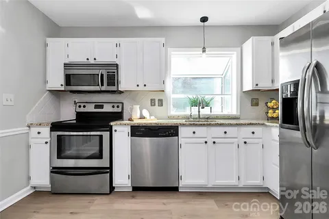 a kitchen with stainless steel appliances white cabinets a stove a sink and a window