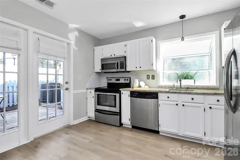 a kitchen with granite countertop white cabinets a window and a stove