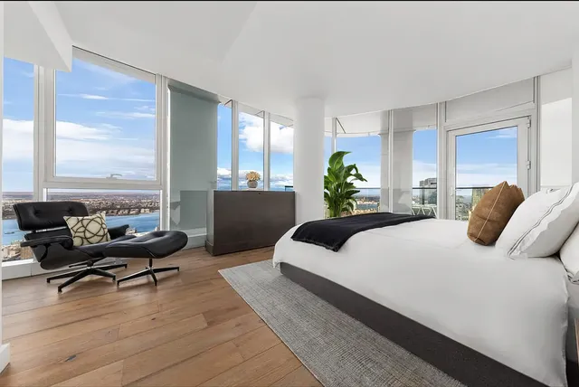 a bedroom with a bed couch and large windows