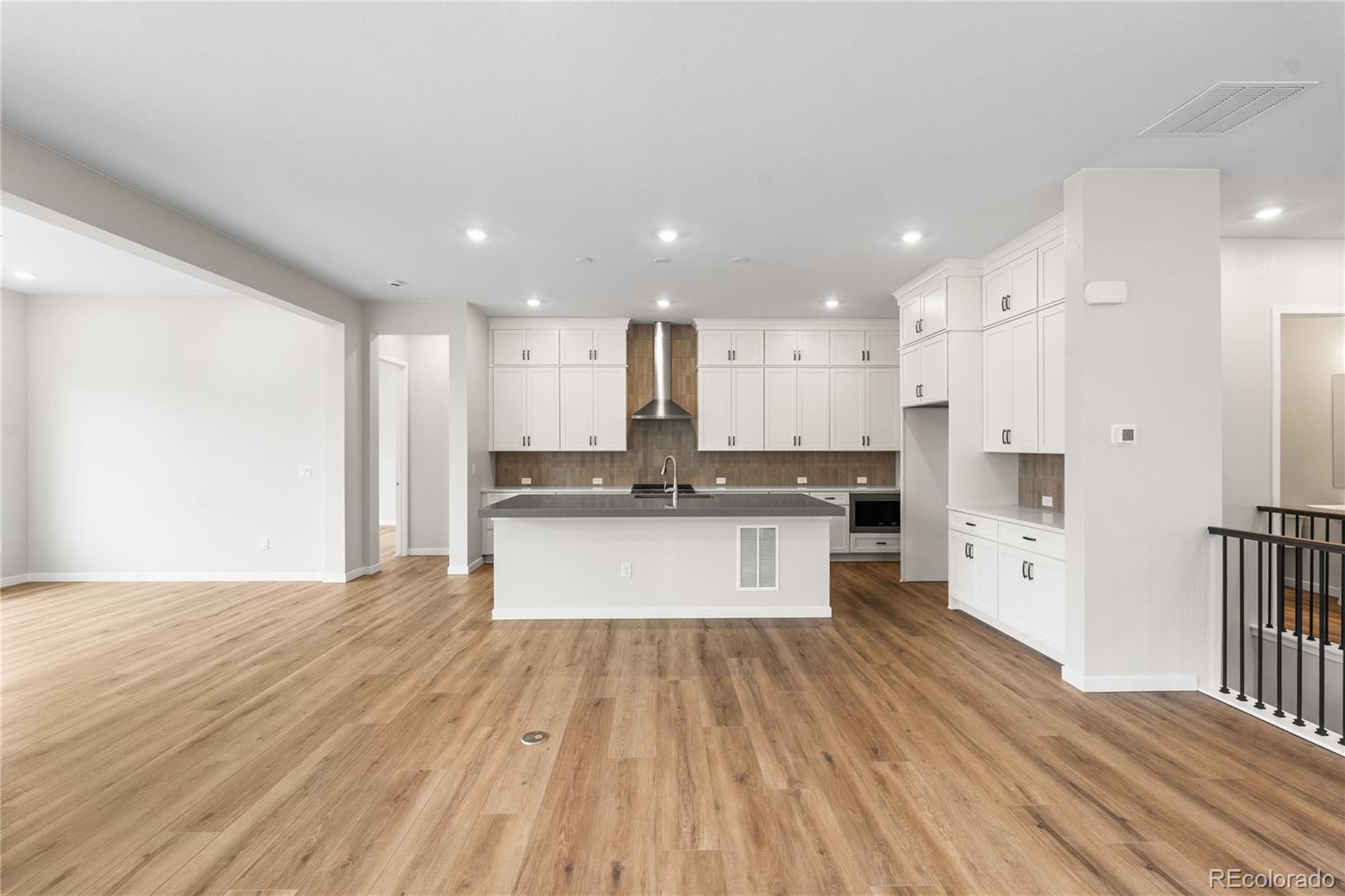 11116 Stonepath Street Littleton, CO 80125 - Photo 11 of 31 a large kitchen with a center island wooden floor stainless steel appliances and cabinets