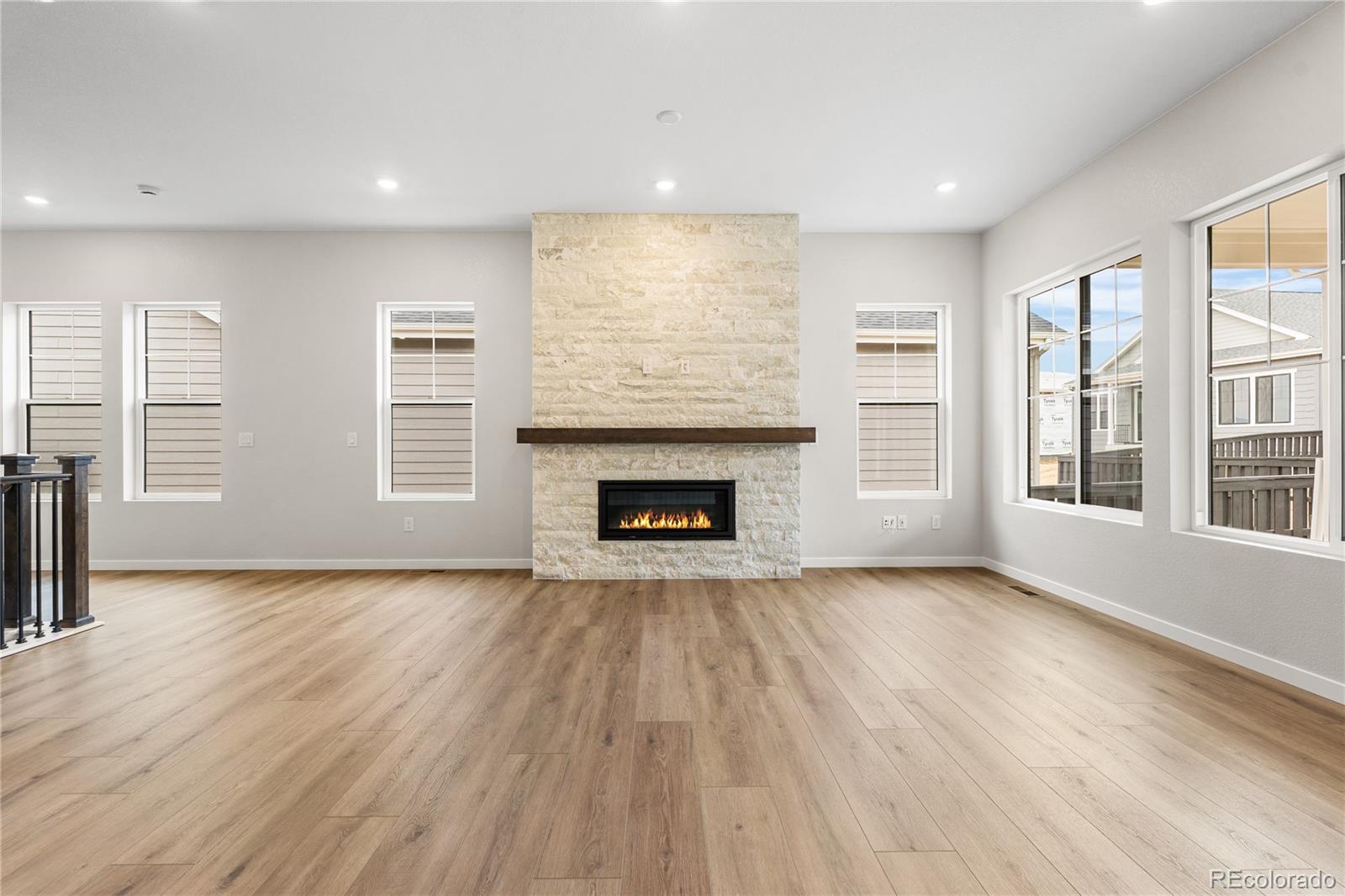 11116 Stonepath Street Littleton, CO 80125 - Photo 9 of 31 an empty room with wooden floor fireplace and windows
