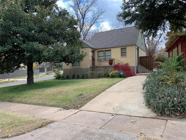 a front view of a house with a garden and trees