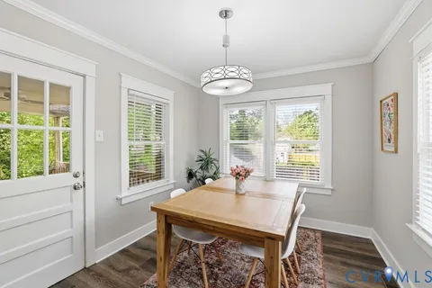 a kitchen with stainless steel appliances granite countertop a sink a stove a refrigerator a dining table and chairs with wooden floor