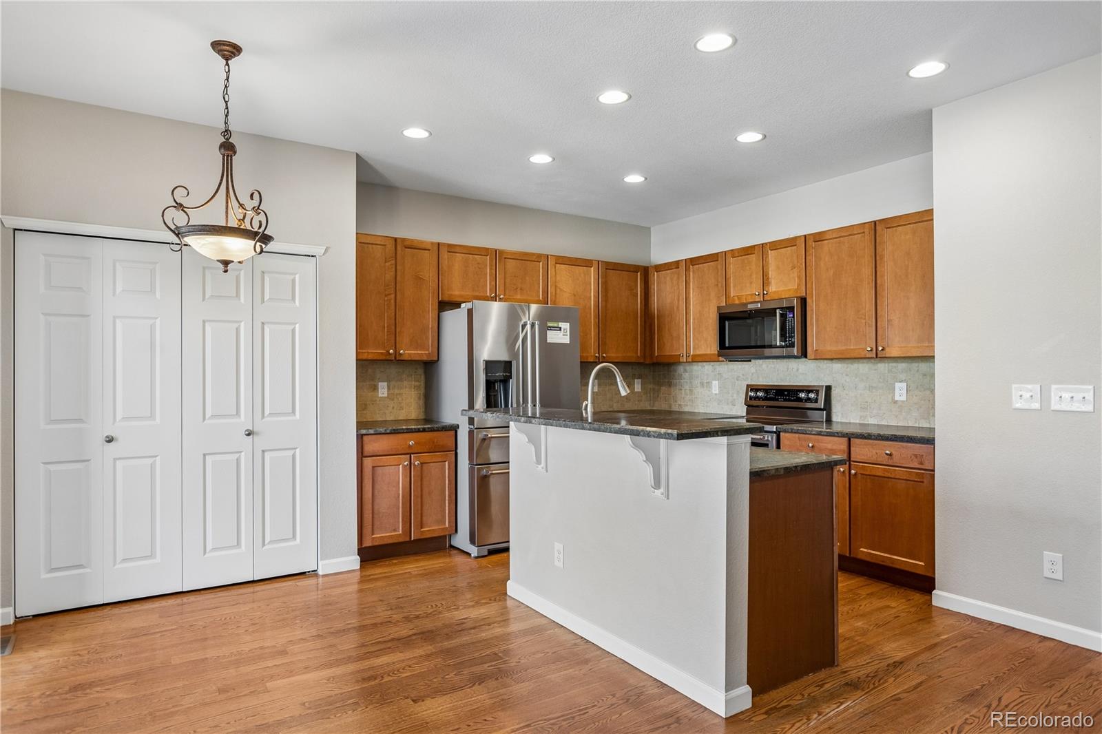 5031 South Rome Street Aurora, CO 80015 - Photo 7 of 39 a kitchen with stainless steel appliances granite countertop a refrigerator a stove a sink and a center island