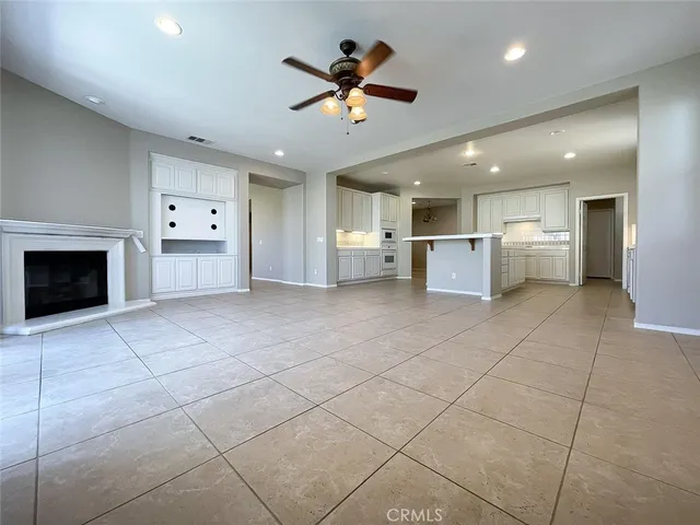 a view of an empty room with a ceiling fan and fire place