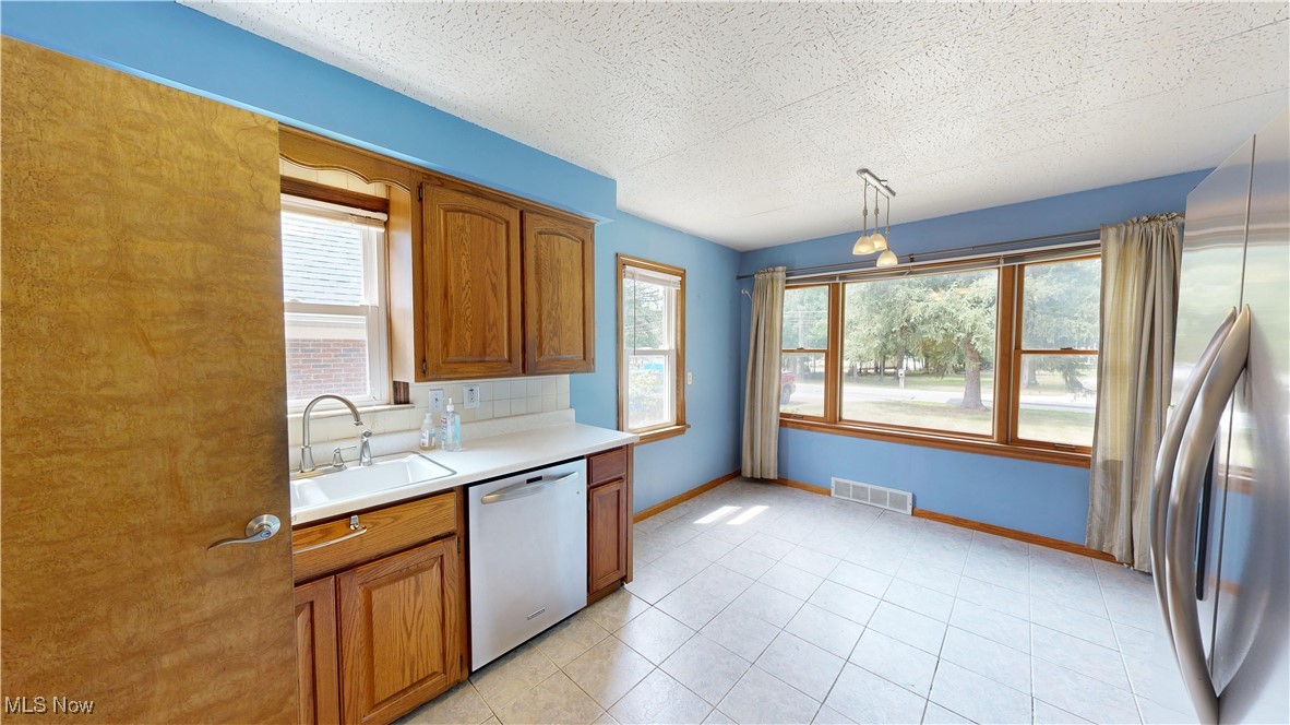 29280 White Road Wickliffe, OH 44092 - Photo 5 of 43 Kitchen with sink, appliances with stainless steel finishes, a healthy amount of sunlight, and light tile patterned floors