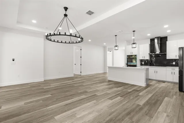 a view of a kitchen with granite countertop stainless steel appliances cabinets a counter space and a chandelier