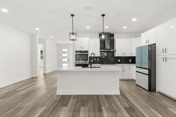 a kitchen with stainless steel appliances granite countertop a sink a stove and a wooden floors