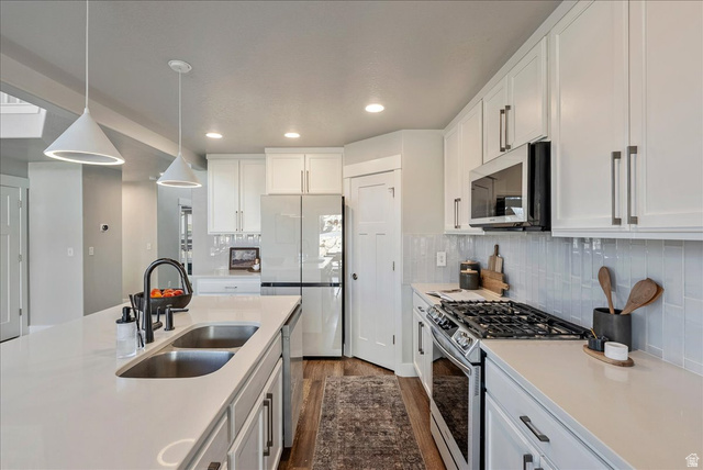882 Spring Dew Lane Lehi, UT 84048 - Photo 13 of 46 Kitchen with stainless steel appliances, dark wood-style floors, white cabinetry, and tasteful backsplash