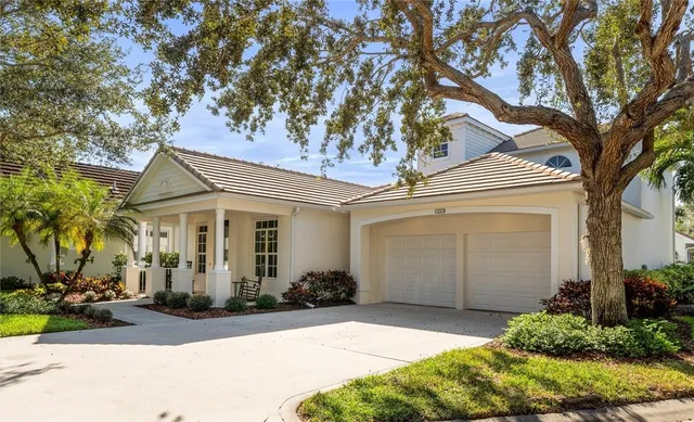 a view of a white house with a tree and plants