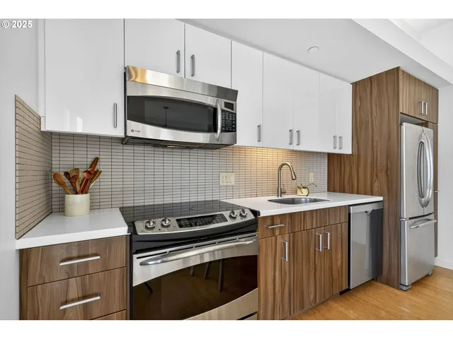 a kitchen with stainless steel appliances a stove a sink cabinets and a microwave