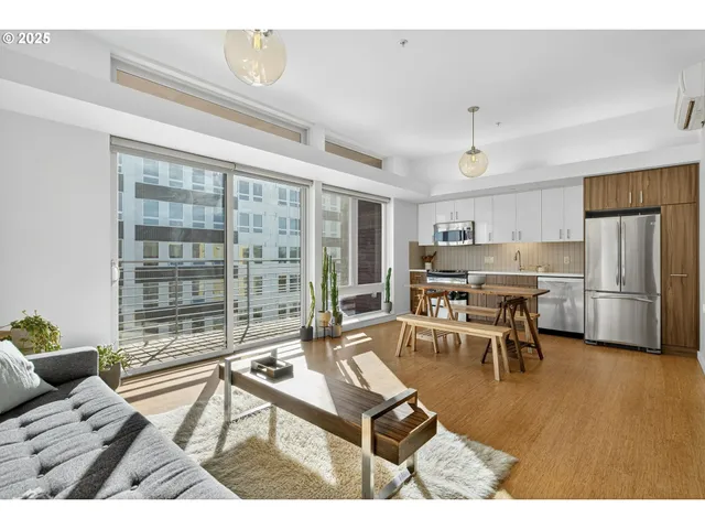 a living room with furniture a large window and stainless steel appliances