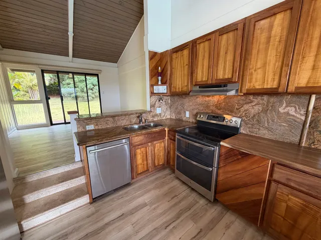a kitchen with granite countertop wooden cabinets stainless steel appliances and a window
