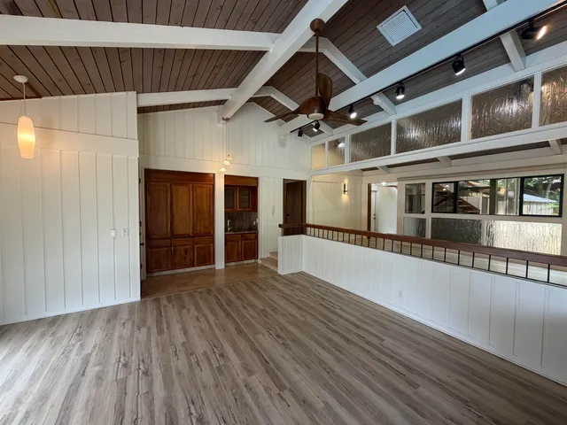 a view of empty room with wooden floor and fan