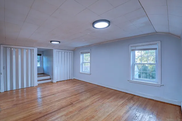 an empty room with wooden floor and windows