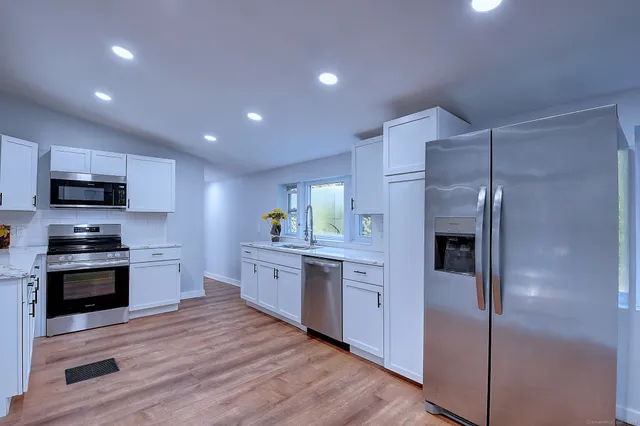 a large kitchen with stainless steel appliances kitchen island granite countertop a stove and a refrigerator