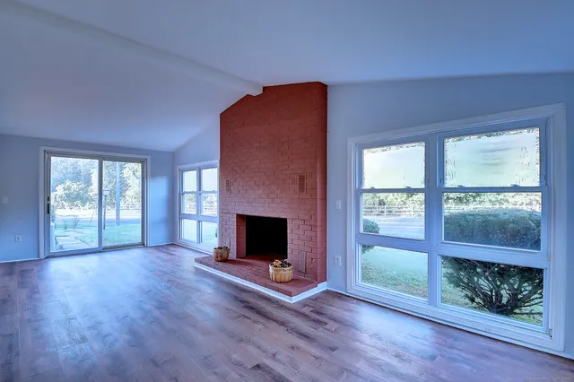 a view of empty room with wooden floor and fireplace