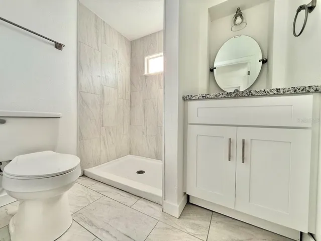 a bathroom with a granite countertop sink mirror and toilet