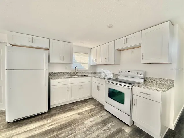 a kitchen with granite countertop white cabinets and white appliances
