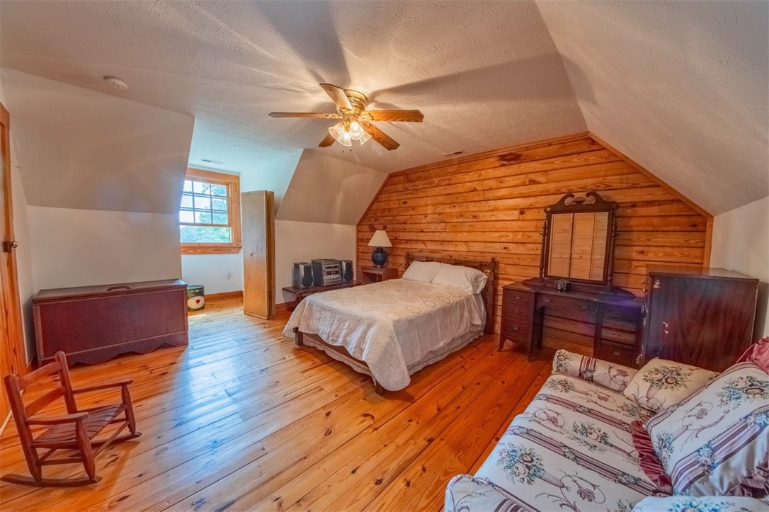 846 Twiggs Ferry Road Hartfield, VA 23071 - Photo 11 of 28 Bedroom with a textured ceiling, wood-type flooring, lofted ceiling, a ceiling fan, and wood walls