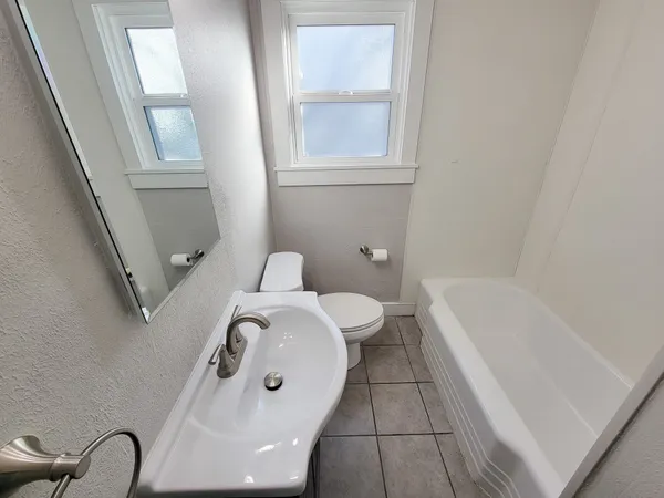 a bathroom with a bathtub a toilet a sink and a mirror