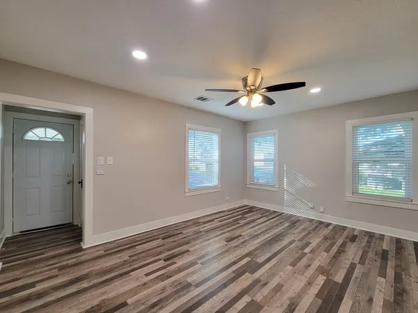 a view of an empty room with a window and a kitchen