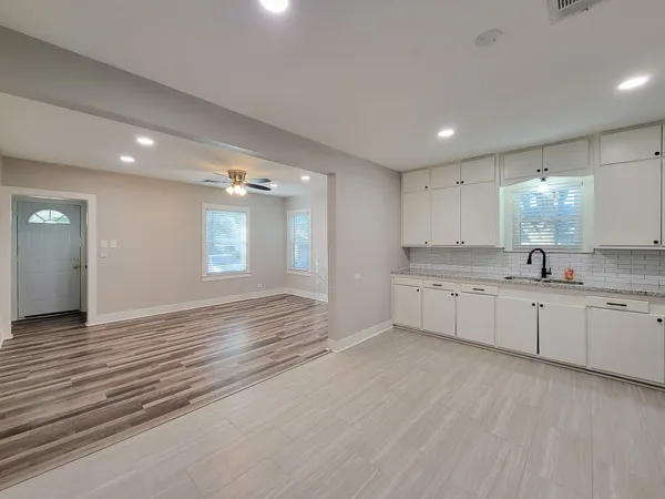 a large white kitchen with kitchen island white cabinets and wooden floor