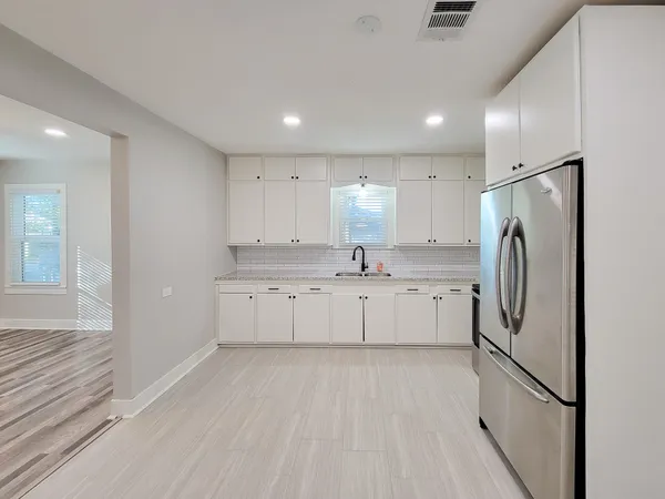 a kitchen with white cabinets and refrigerator