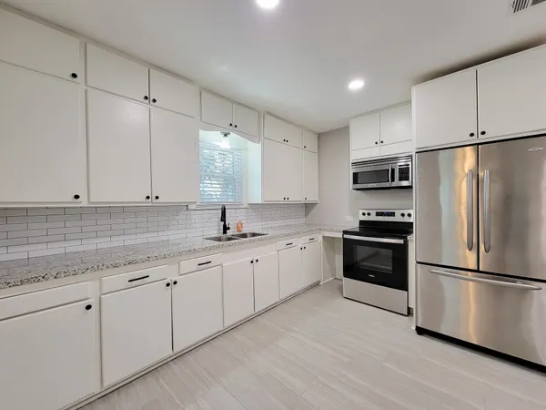 a kitchen with granite countertop white cabinets and stainless steel appliances