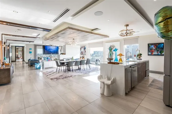 a kitchen with stainless steel appliances kitchen island granite countertop a refrigerator a sink a stove and white cabinets with wooden floor