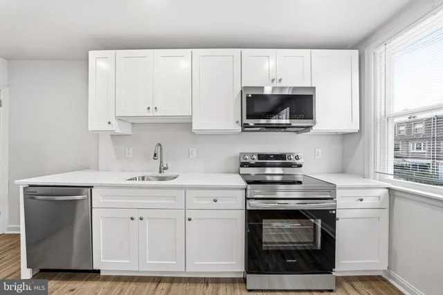 a kitchen with white cabinets and appliances