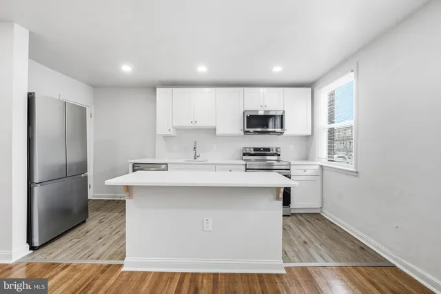 a kitchen with kitchen island a sink stainless steel appliances and cabinets
