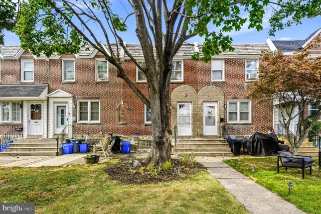 a view of a white house with large windows and a small yard