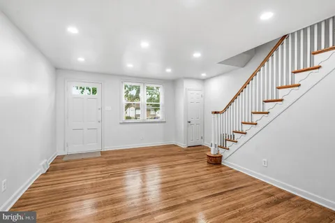 a view of an empty room with wooden floor and stairs