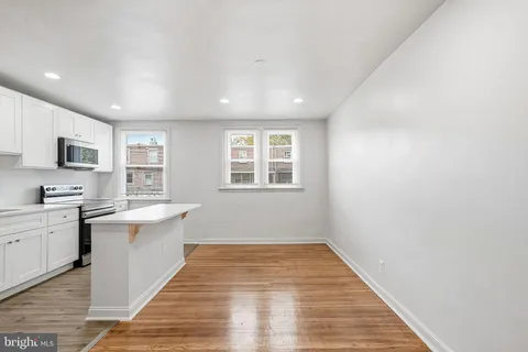 a view of a kitchen with wooden floor and stainless steel appliances
