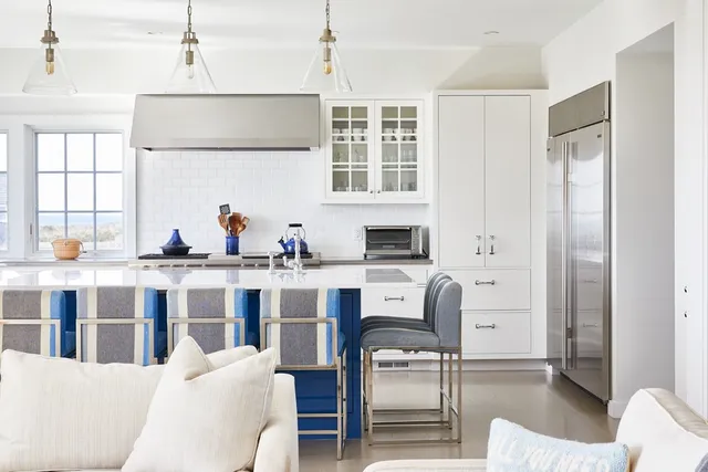 a kitchen with stainless steel appliances kitchen island granite countertop a dining table chairs and a refrigerator