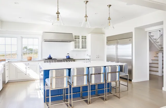 a large white kitchen with granite countertop a stove a sink and white cabinets