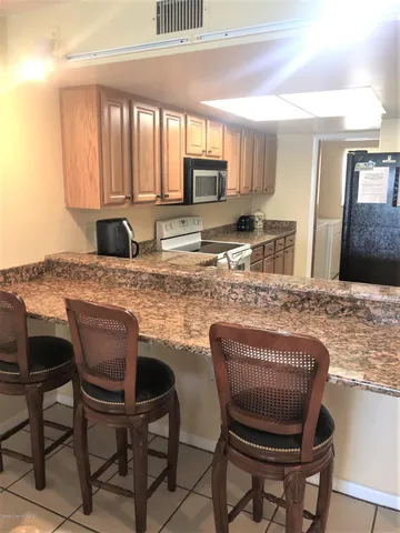 a kitchen with stainless steel appliances granite countertop a stove top oven a sink a dining table and chairs