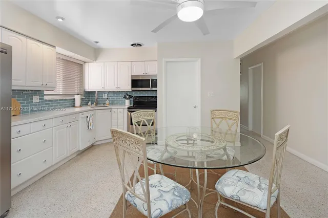 a kitchen with stainless steel appliances granite countertop a sink a stove a dining table and chairs